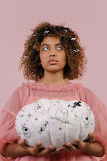 young black woman with weird eyes and holding white pumpkin with strange carvings.