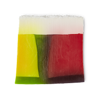 A cut piece of rectangular green, yellow and blue soap with a white popping candy layer on a bright background