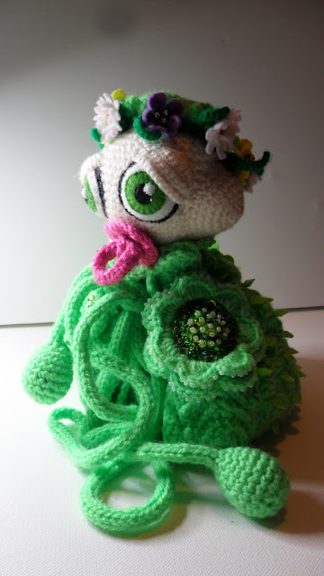 Cute Amigurumi crochet baby caterpillar, with beautiful big manga eyes, she looks sleepy. It has felt flower garland around it's head. Bright green body with Irish Crochet flowers, the flower are full beadwork, she has a bright pink dummy. Pompoms tie under her neck