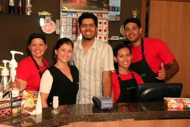 Former café team striking a pose at the cash register for a photo.