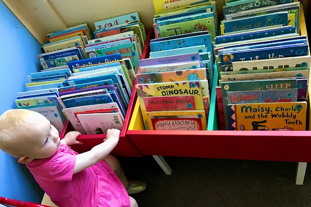 a toddler in front of lots of picture books in a library