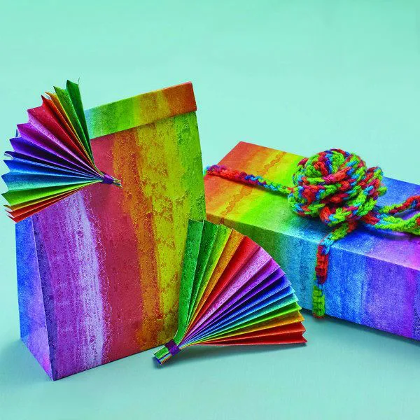 rainbow gift wrap with paper fan ornaments and multicolor yarn bow