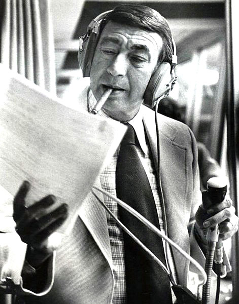 announcer Howard Cosell with headphones on; smoking a cigarette and looking at a printed paper