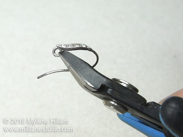 Using flush cutters to cut open the loop of the earring wire.