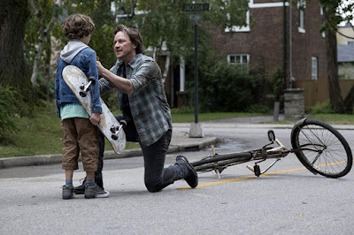 It Chapter Two 2019 movie still where James McAvoy's Bill Denbrough stops a child named Dean (Luke Roessler) in the middle of the street to warn him that Pennywise is after him