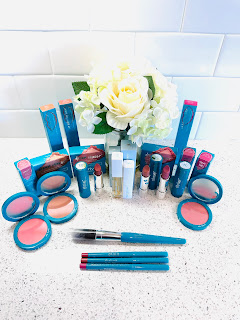 A collection of Thrive Causemetics and Bigger Than Beauty products including lipstick, lip liner, blush, blush brush, liquid balm treatment, and lip oil.