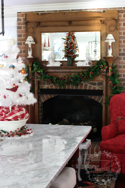 Farmhouse kitchen mantel decorated with garland, a Christmas tree and white glittery deer.