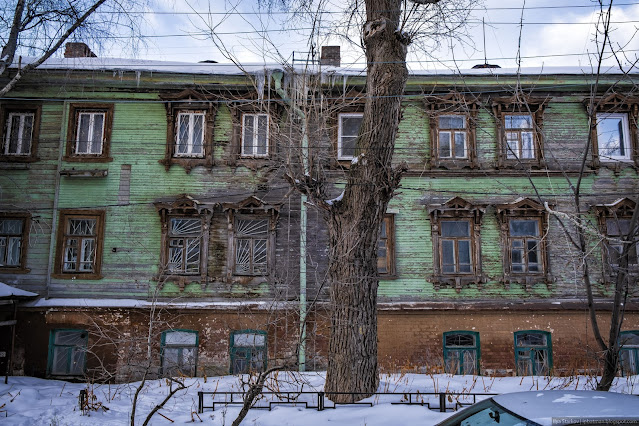 Зеленый деревянный дом с ажурными наличниками