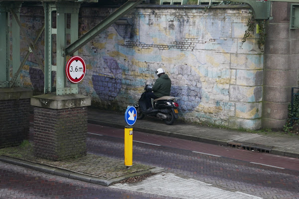 Stilstaande scooterrijder onder viaduct