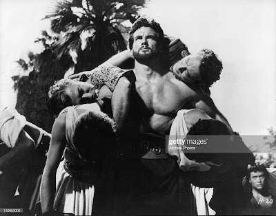 Hercules (Steve Reeves) carries four Argonauts back to their ship, escaping eventual death from the Amazons in HERCULES (1958)