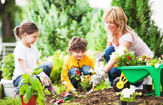 A mother with her two children tending to the garden