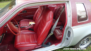 Bright red vinyl seats shown inside the silver 1975 Chevy Monza Towne Coupe.
