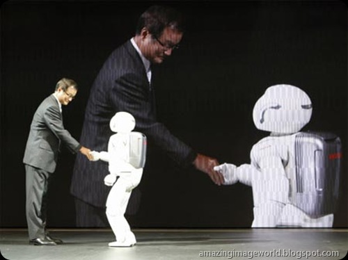 Takanobu Ito shakes hands with an Asimo 001