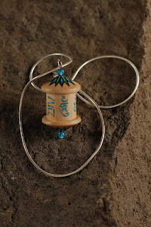 A WOODEN PRAYER WHEEL PENDANT