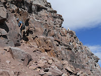 A mountain goat watches a human mountain goat on Pyramid Peak