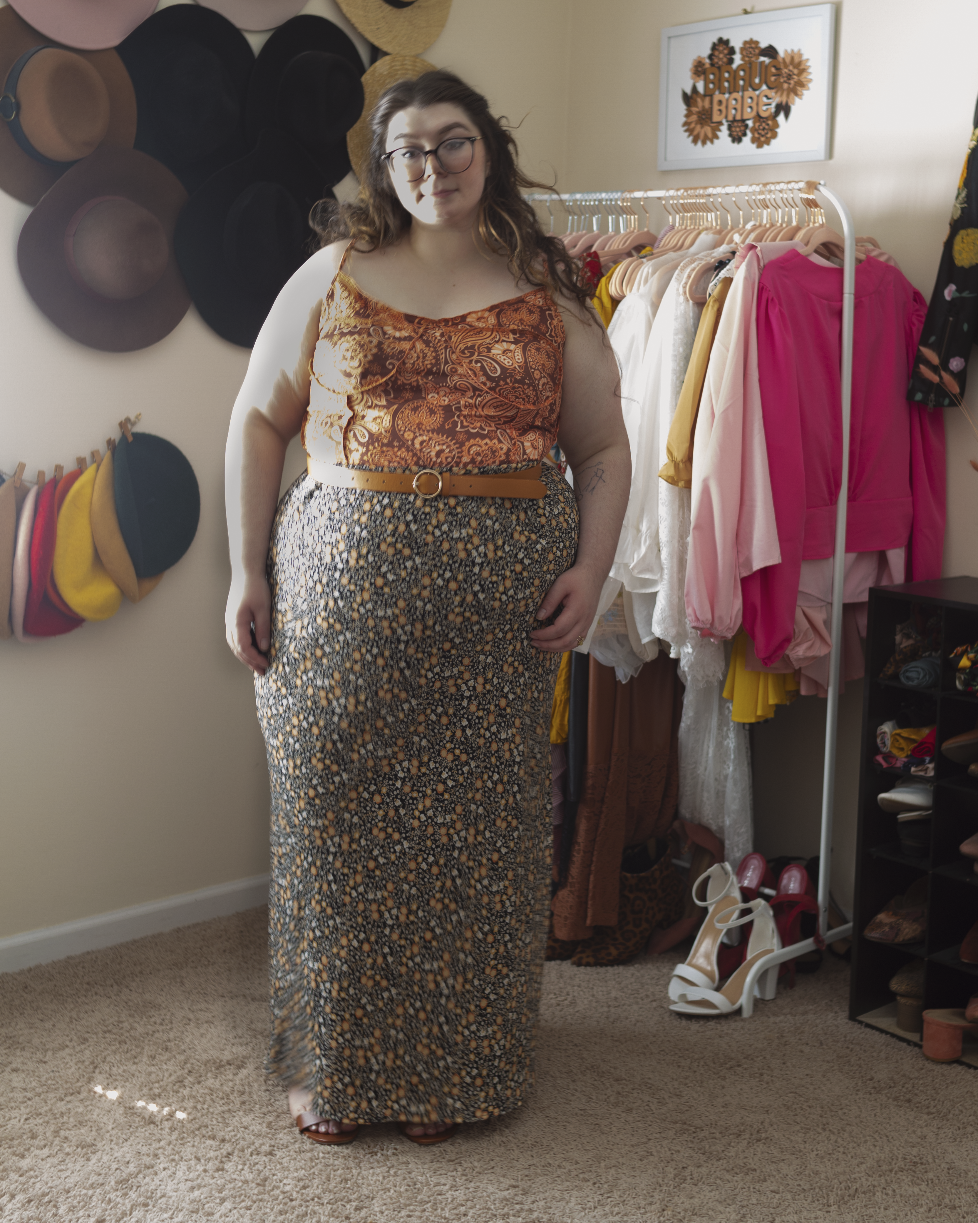 An outfit consisting of an orange and brown bandana print top and a black, brown, and orange floral skirt and cognac brown heeled sandals.