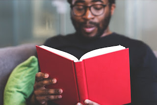 Black man wearing glasses reading a book