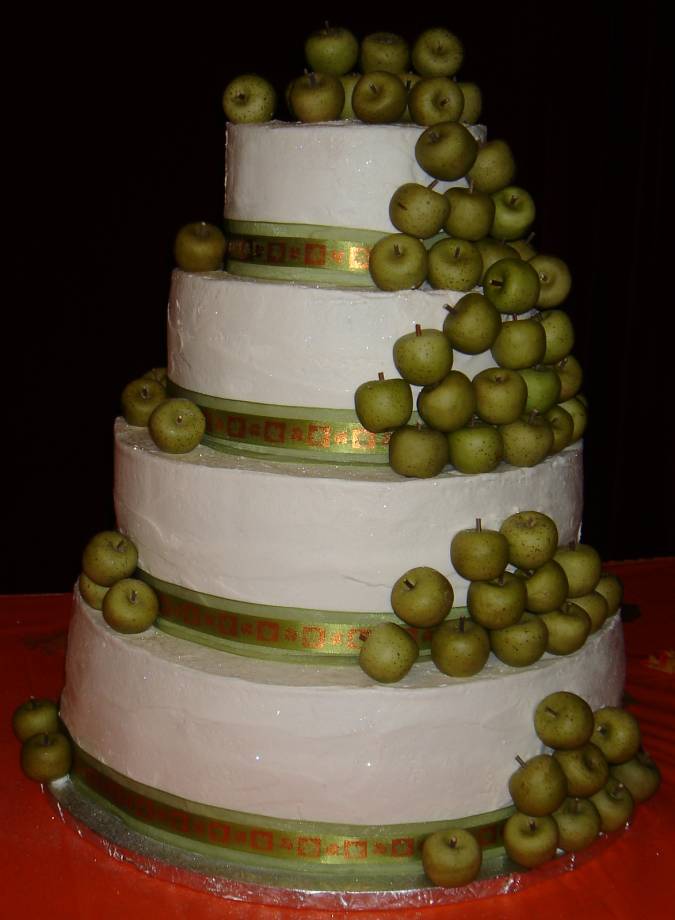A white wedding cake featuring many green apples set over four round tiers