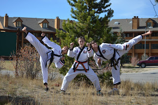 Black belt mom does a kick with her two taekwondo kids