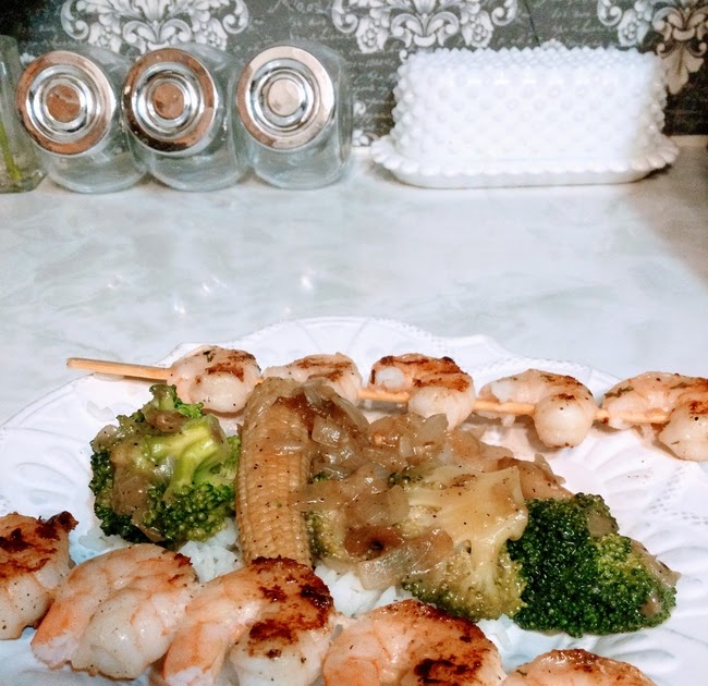 Grilled shrimp with vegetables and rice plated on vintage white scalloped dish on top of counter