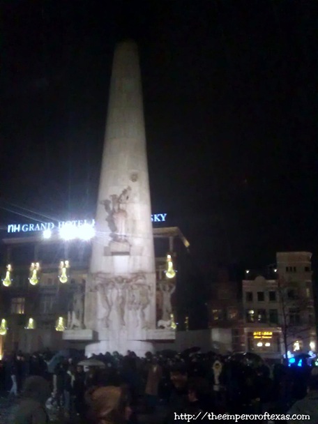 Dam Square. 26 minutes to THE NEW YEAR 2013 (LIVE caption delivered to Fb: “Monument of the Fallen Dead. DAM SQUARE. One worry: that phone holds the soaked rain. 26 minutes to NEW YEAR.”)