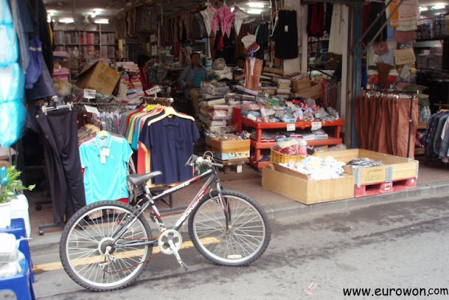 Tienda coreana con una bicicleta delante para que no aparquen lo coches