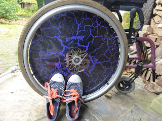 This is an image of my shoes with orange laces beside my manual wheelchair.