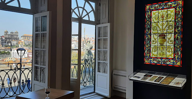 janelas com vista para o Porto, copo de vinho do porto, mesas e bancos, exemplo de vitral num painel