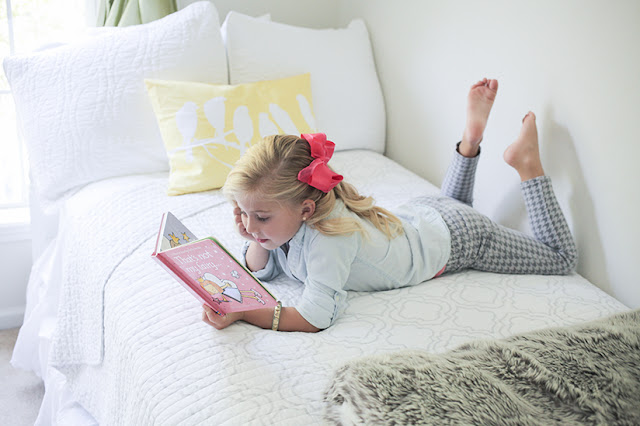 Amy West's daughter Sienna reading book on bed