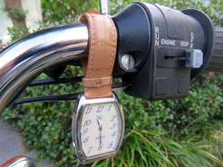 Wrist watch hanging from handlebar.