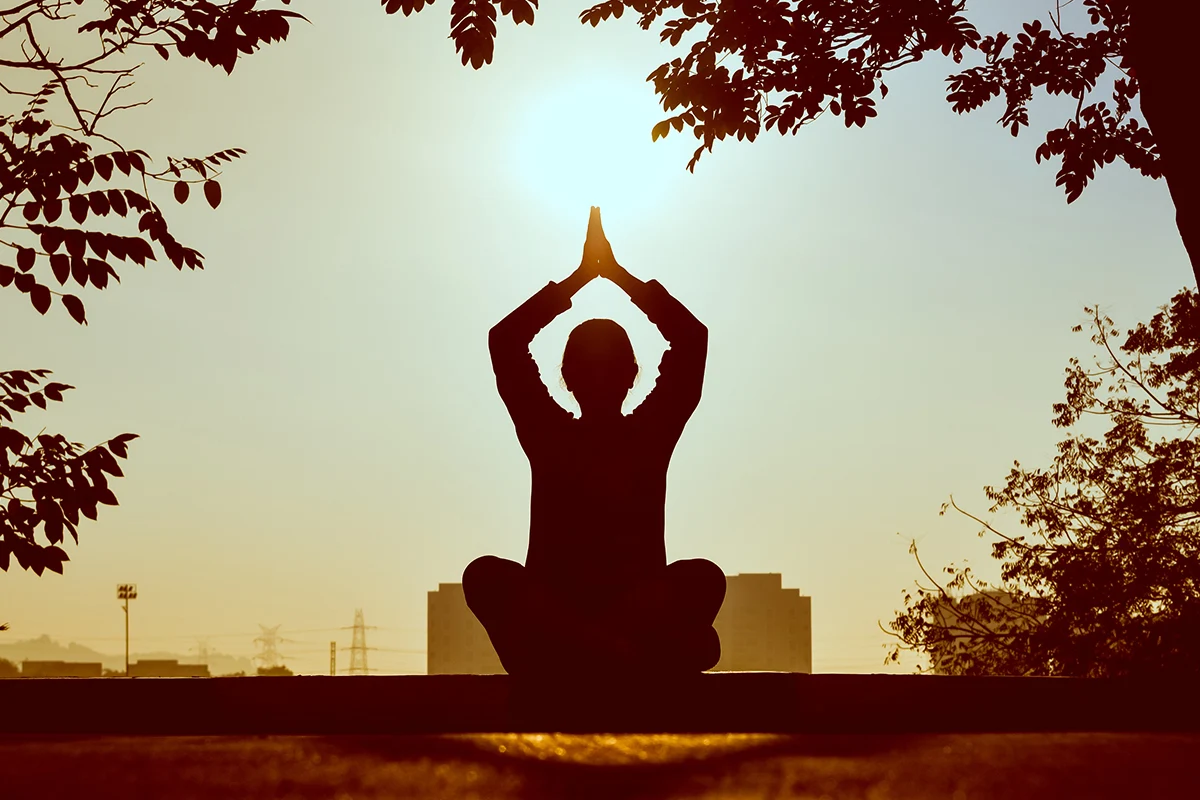 a sillouette of a meditating woman in a garden