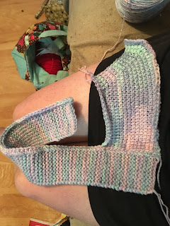 Being worked in pastel variegated yarn, there is a strip of knitted garter stitch with a slightly tapered point of Tunisian crochet attached to the far right side of it.