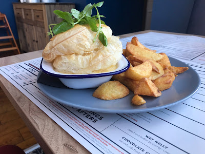 pie and chips on a blue plate on top of a menu on a wooden table