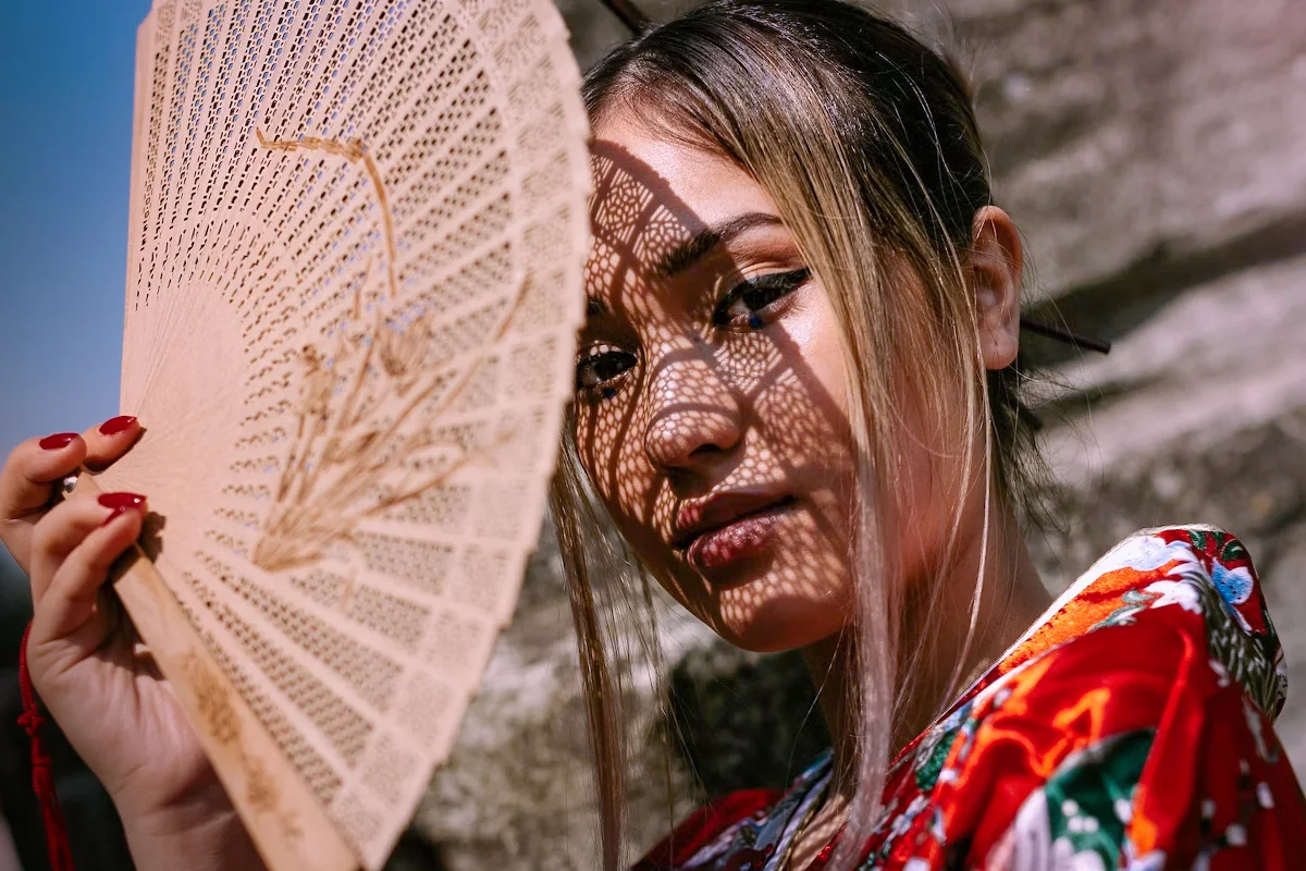 a portrait of a beautiful young woman in silky robe and wooden hand fan