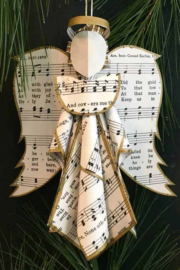 sheet music angel ornament with gold metallic inked edges hanging on tree