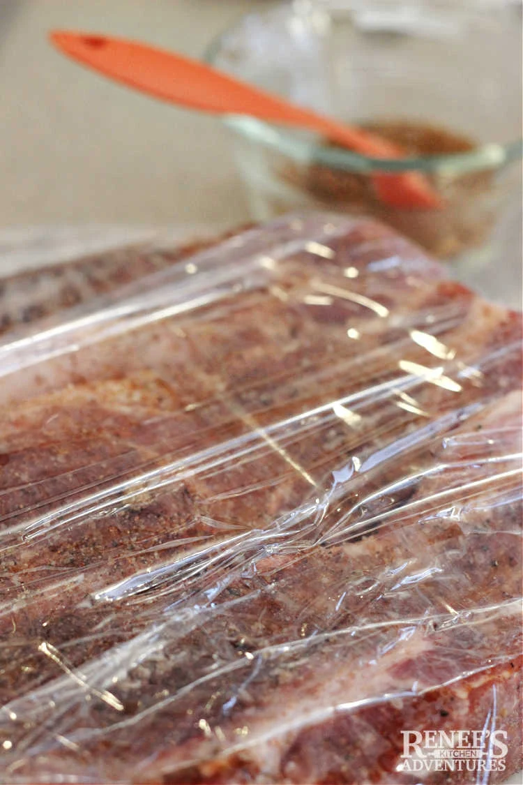 Seasoned country style ribs wrapped in plastic wrap and ready for refrigerator