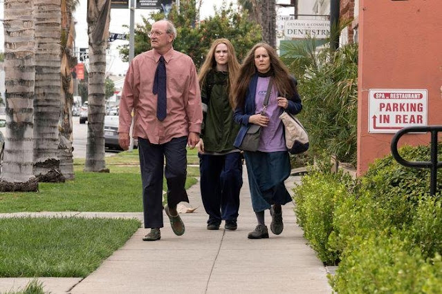 Film still from Kajillionaire. A man and two woman walking down the street.