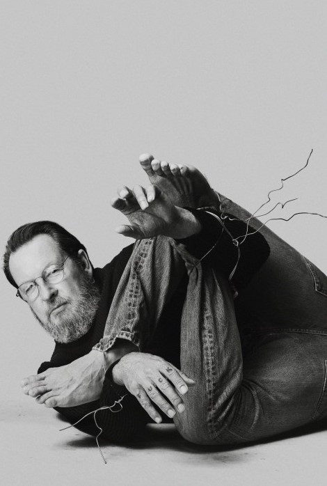 Photoshopped pic of Lars von Trier in a contorted position, his F U C K knuckle tattoo clearly visible