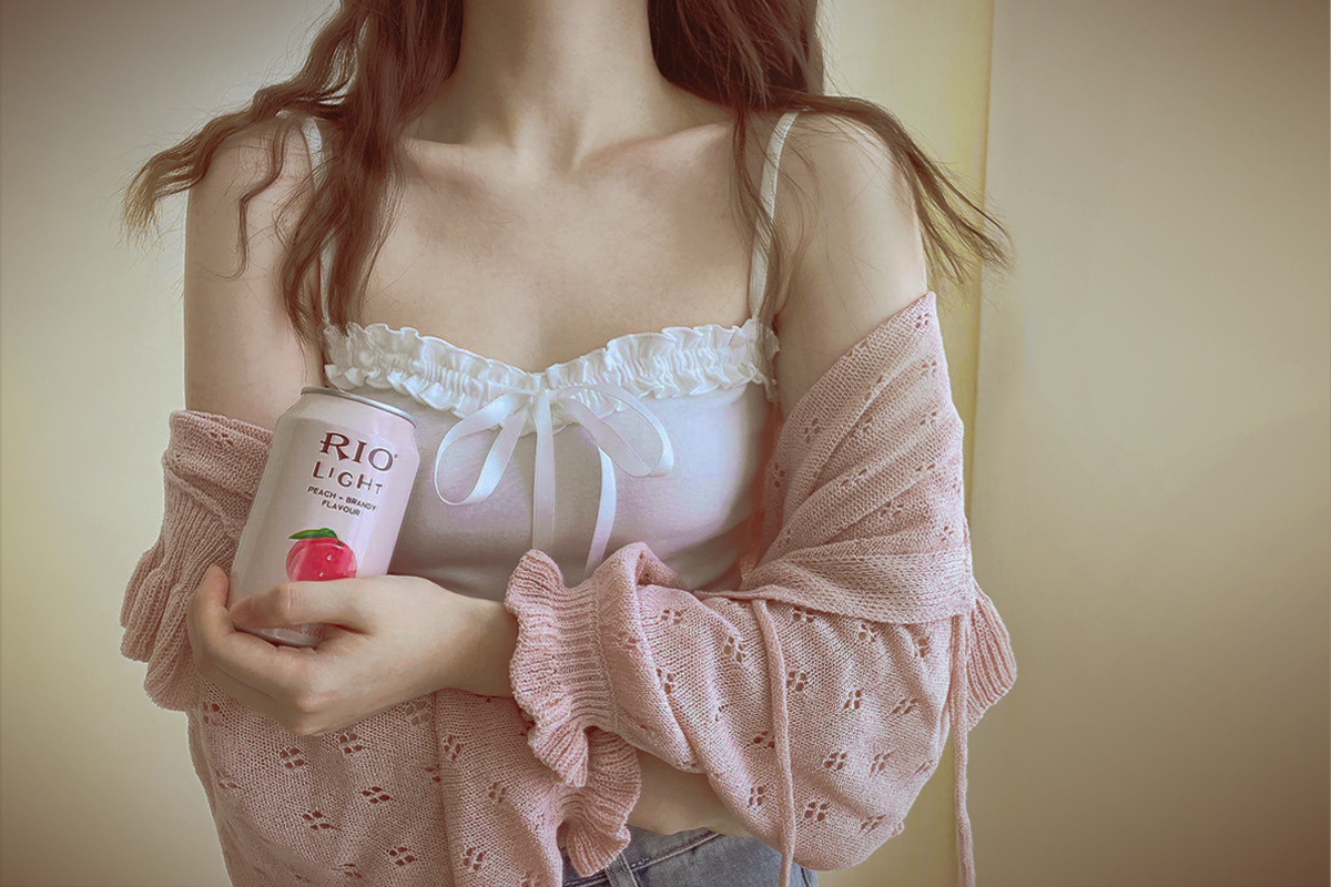 soft girl in ruffled cardigan and crop top is holding pink drink in her hand