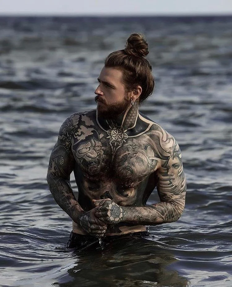 Imagen de un hombre barbudo con tatuajes hipster en negro