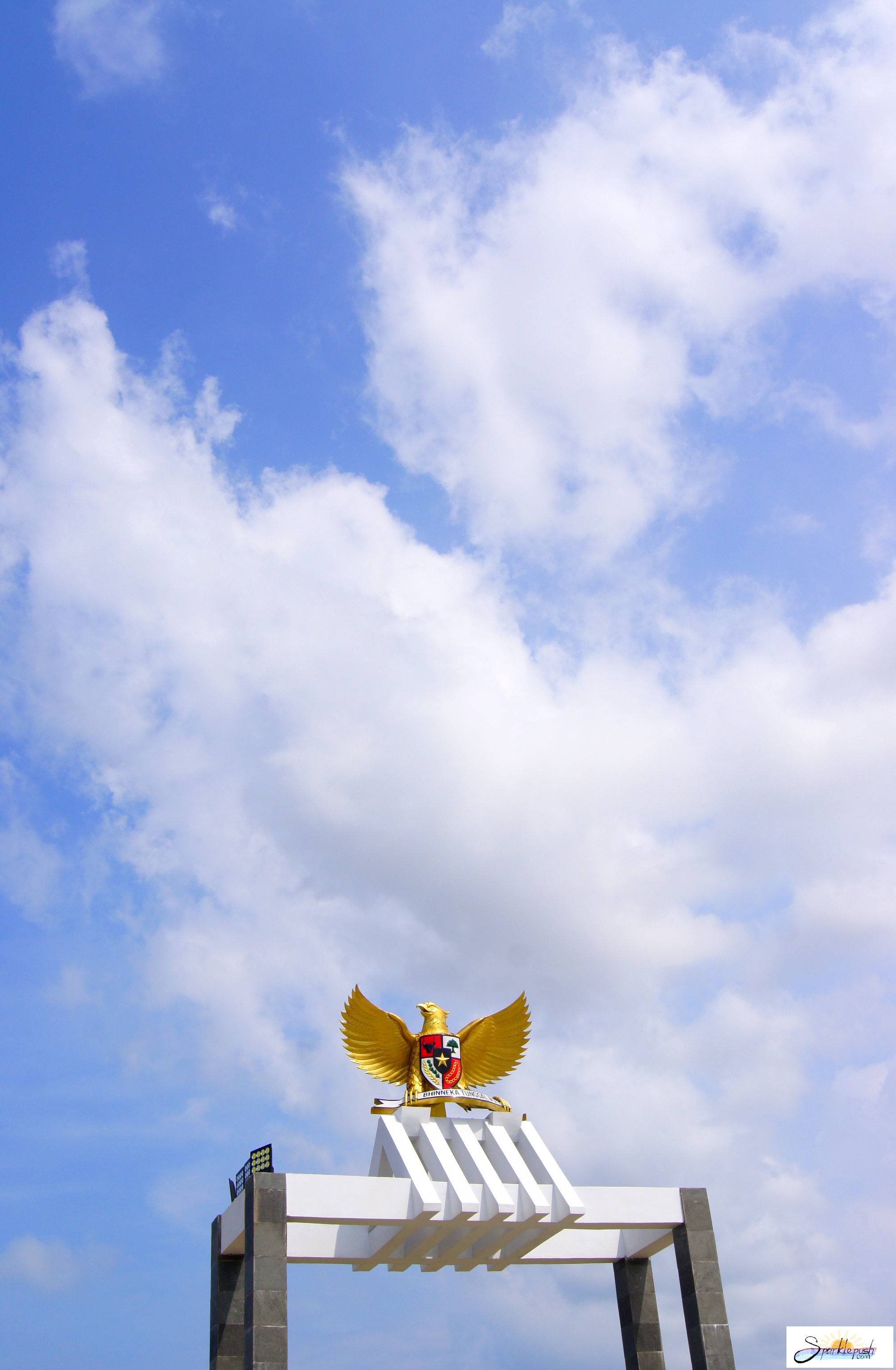 Foto Patung Garuda Pancasila Dengan Background Langit Biru dan Awan Putih