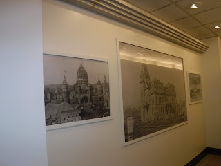 white walls on the skywalk level of the Sioux City Orpheum theatre building with 3 large, framed black and white photos showing buildings from Sioux City Iowa around the turn of the 20th century including a corn palace and the old Woodbury County courthouse