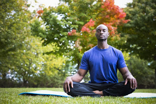 man sitting cross-legged on a yoga mat outside