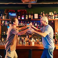 Sports enthusiasts at a bar performing a synchronized handshake known as the "Triple Touchdown Tango."