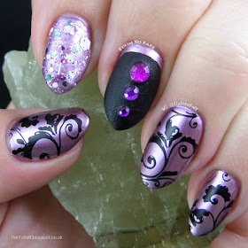 Nail art featuring stamping, glitter, texture, and rhinestones over chrome polish in purple and black tones.