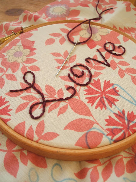 work in progress image of hand embroidered love text onto vintage fabric