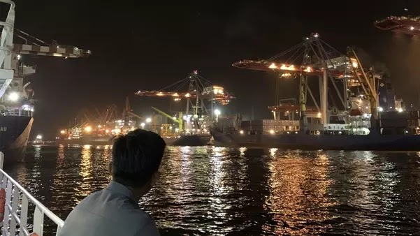 Foto seseorang melihat pelabuhan di malam hari