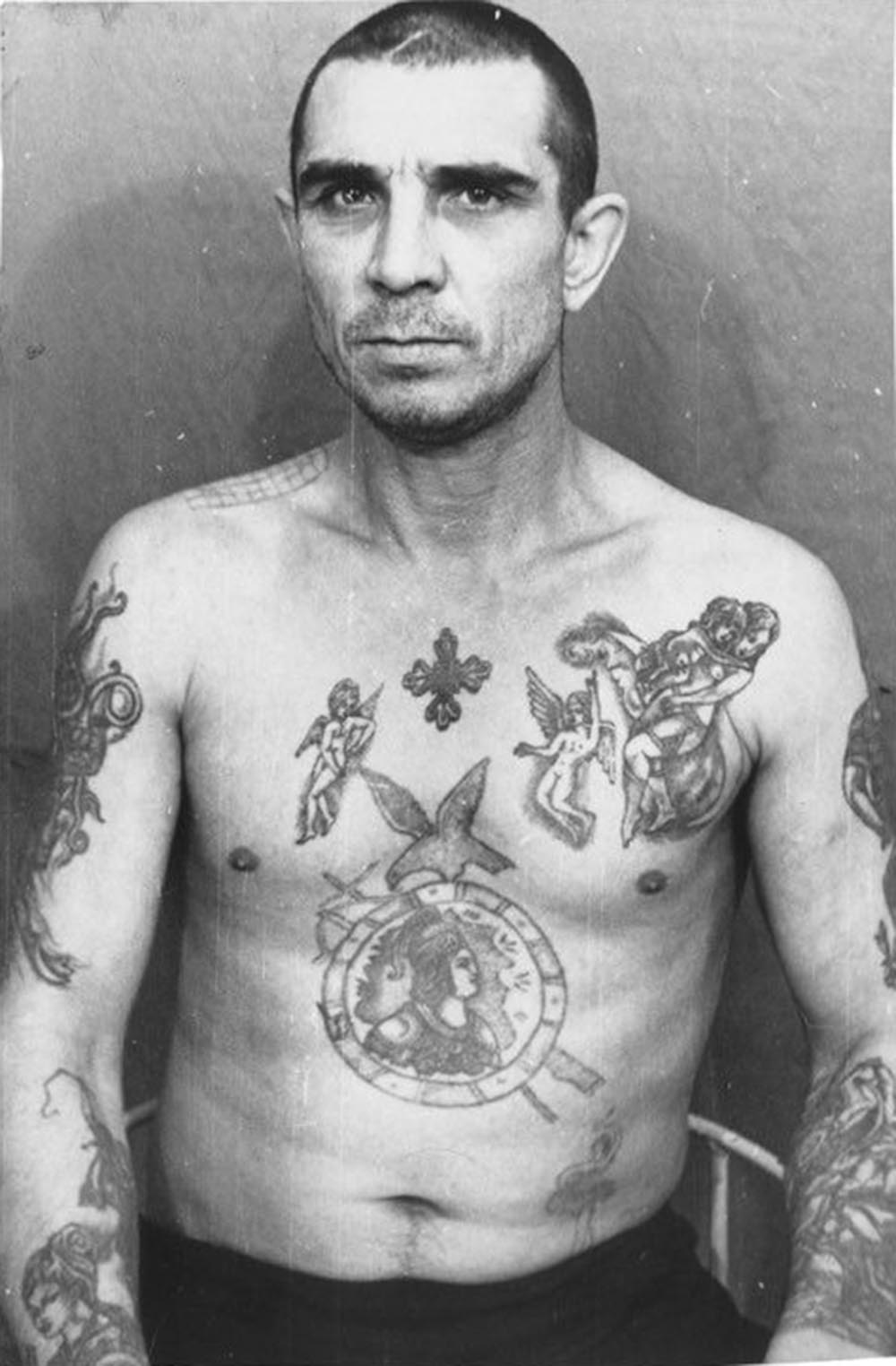 The tattoos on this inmate mimic those of higher ranking criminals. They indicate the bearer has adopted a thief's mentality. However, he does not wear the 'thief's stars;' he is not a 'vor v zakone' or 'thief-in-law,' and therefore holds no real power among this caste.