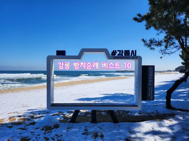 눈-덮힌-백사장-뒤로-보이는-파도치는-바다와-푸른-하늘
