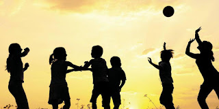 Children playing basketball outside as the sun goes down